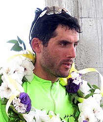 A man with parrot-green color athlete's attire, sunglasses on his head and a flower garland around his neck