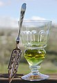 Image 21A reservoir glass filled with a naturally colored verte absinthe, next to an absinthe spoon (from List of alcoholic drinks)