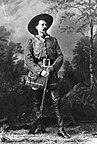 Black-and-white photo of Buffalo Bill in front of a forest backdrop, holding a Winchester