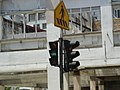 A typical pedestrian crossing traffic light in Kuala Lumpur with a countdown display and a pedestrian crossing sign above it.