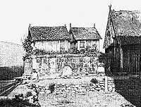 Low stone tomb with a miniature wooden house constructed on top