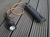 Two-part diving light with lamp assembly at left and battery pack at right, joined by a short cable