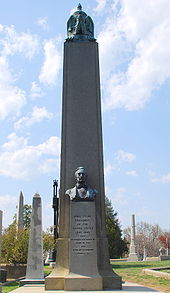 A large obelisk in a graveyard, with a bust of Tyler.