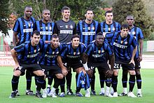 Photographie montrant onze joueurs de football alignés sur deux rangs, vêtus de tenues bleues et noires