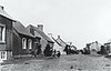 The Kahnawake reserve in 1910: a group of four people stand barefoot in front of a tidy row of houses.