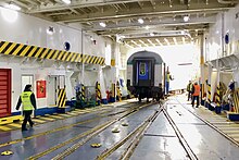 Image showing a railcar on rails inside the white interior of a ferry.