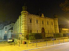 Vue de la façade principale de nuit, éclairée par un dispositif créer à cet effet.