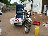 An off-road motorcycle fitted with knobbly mud tyres and a single sidecar, which has a cover over the passenger seat and a Unicef logo on the front