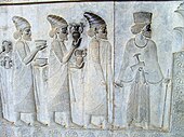 Relief din Persepolis (Iran) care înfățișează oameni care duc blouri și amfore