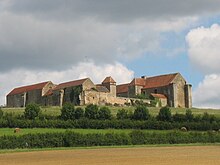 Photo d'un château ancien entouré de champs et prairies.