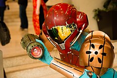 Femme dans un costume jaune et rouge de Samus Aran (cosplay).