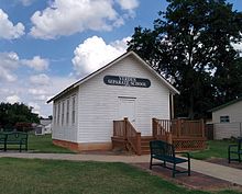 A one-room schoolhouse with white-painted wooden siding