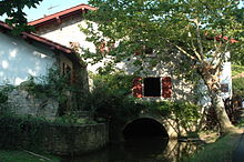 Vue d'un bâtiment dont les fondations sont traversées par un cours d'eau.