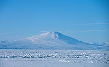 Distant view over an ice-covered sea of a conical mountain