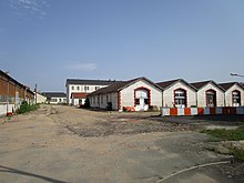 Photographie en couleurs de l'alignement des anciens hangars d'une caserne.