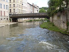 Rivière encadrée de bâtiments et franchie par un pont.