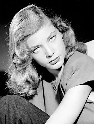 Lauren Bacall in black and white, her head tilted down with her eyes pointed up at the camera