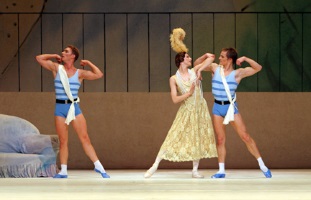 female dancer in long 1920s frock and feathered head-dress, with two male dancers dressed as athletes dancing on either side of her