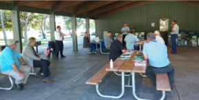 People seated at picnic tables in a pavilion