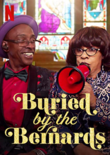 Debbie Bernard is speaking into a loudspeaker and looking off-camera, while her brother Kevin looks at her, smiling. They are inside a church standing in front of large colorful stained glass windows.