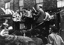 The Quarrymen performing in Rosebery Street, Liverpool on 22 June 1957.[1] (Left to right: Hanton, Griffiths, Lennon, Garry, Shotton, and Davis)