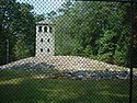 Mound and observation tower viewed through protective fence