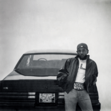 A black-and-white vignetted photo of Lamar leaning against the back of the titular GNX