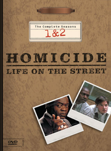 A DVD box-set cover with a background resembling a brown file folder, including a metal clip at the top. The words "Homicide: Life on the Street" are printed in the middle of the cover, with the words "The Complete Seasons 1 & 2" above it. Underneath the words are two images resembling photographs, one with a man wearing a suit jacket looking straight forward and pointing with his index finger, and the other of two men wearing dress shirts leaning forward and looking sideways.