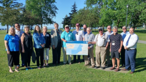 People posing for an outdoor group photo and holding a map