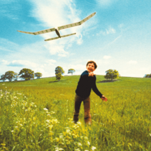 Blunt as a young boy throwing a toy plane in a grassy field