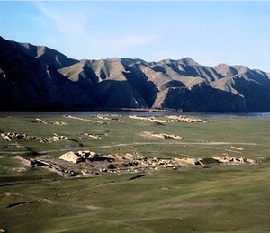 Landscape photograph of ruined structures on a grassy plain.